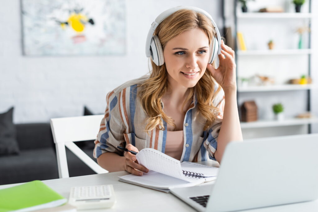junge Frau mit Kopfhörern am PC; AdobeStock/lightfiels studios