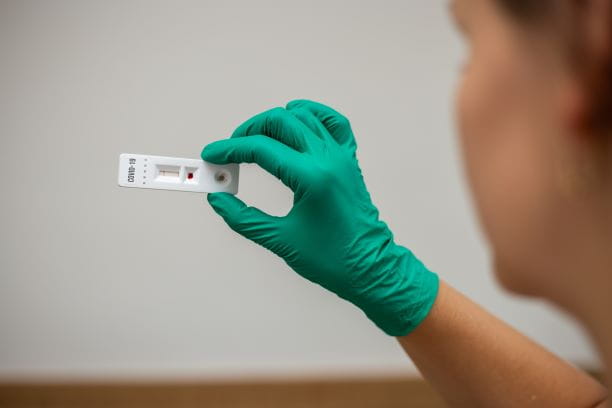 Hand hält Antigen-Schnelltest