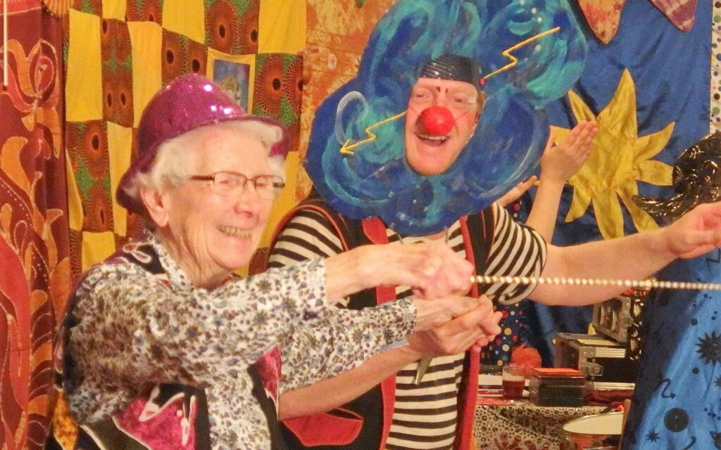 Bewohnerin mit Clown hat Spaß beim Jonglieren im Zirkus in der Pflegeeinrichtung Altenzentrum Hospital.