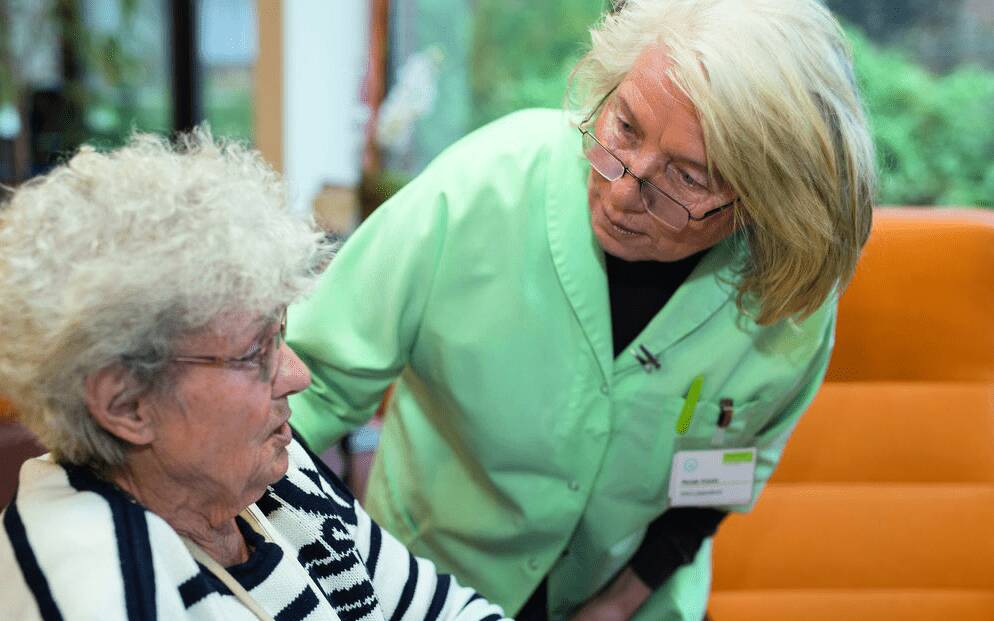 Ehrenamtliche Betreuuerin einer Seniorin zugewandt