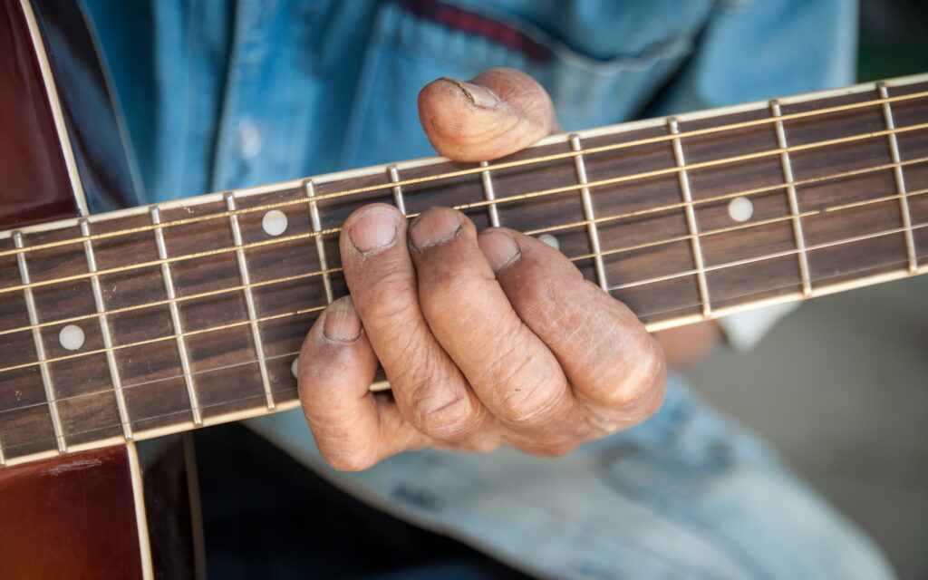 Senior spielt Gitarre - Detailaufnahme der Hand an der Gitarre