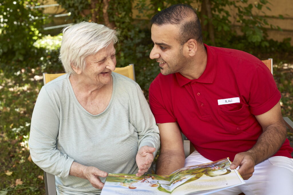 Seniorin und Betreuer betrachten gemeinsam ein Buch