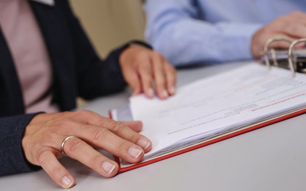 Hand in Nahaufnahme blättert in Dokumentationsordner