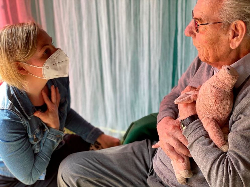 Senior und Betreuerin mit Gluecksschwein, Foto: Awo Seniorenzentrum Moers