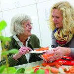 Seniorin und Betreuerin beim Gemüsescheiden