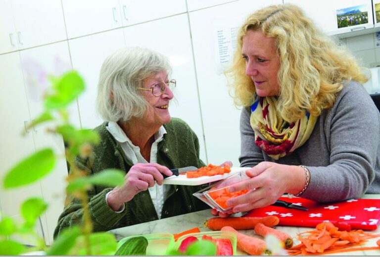 Seniorin und Betreuerin beim Gemüsescheiden