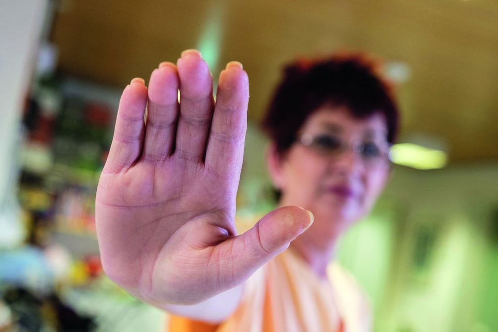Mitarbeiterin hebt abwährend die Hand