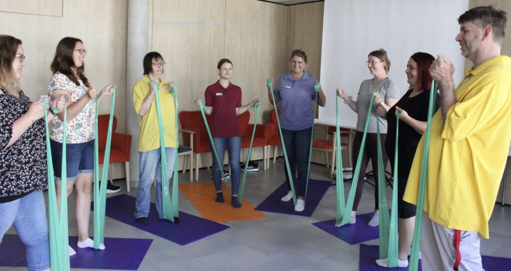 Kräftigungsübungen mit TheraBand: In einer heiteren Atmosphäre erhalten Mitarbeitende der Stiftung Liebenau im Haus der Pflege St. Raphael in Oberteuringen praxistaugliche Tipps für ihre Gesundheit.