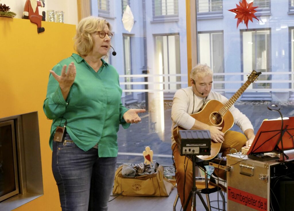 Kerstin Schöppner erzählt im Altenwohnhaus St. Anna in Haltern am See eine Weihnachtsgeschichte. Für die musikalische Begleitung sorgte Hans-Jürgen Lehmacher, der Weihnachtslieder anstimmt und dazu Gitarre spielt.