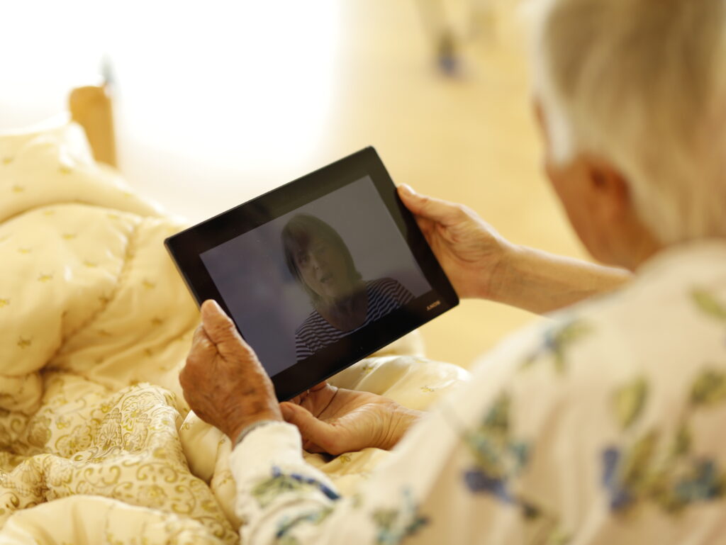 Bettlägerige Bewohnerin mit Tablet