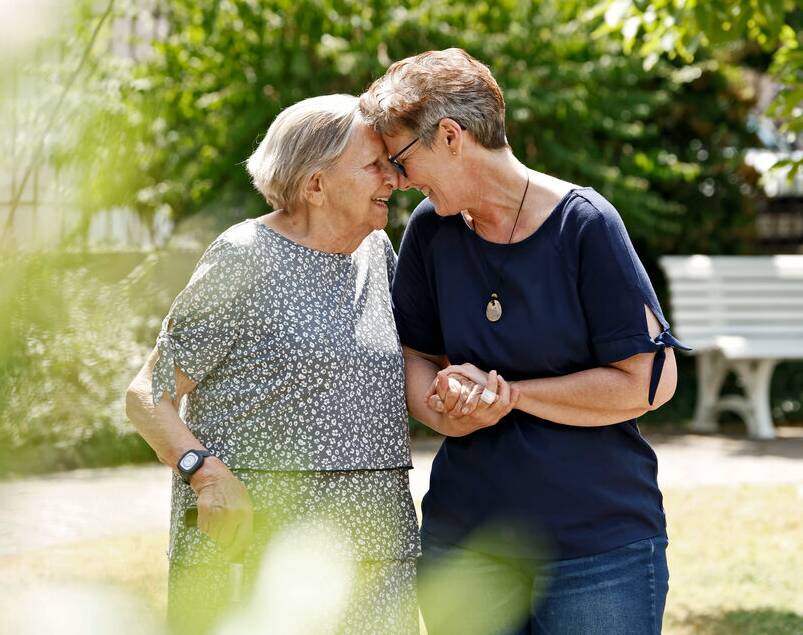 Betreuerin und Seniorin innig beieinander