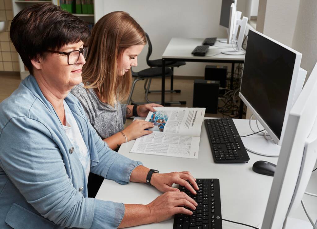 Leitungskraft und jüngere Frau am PC