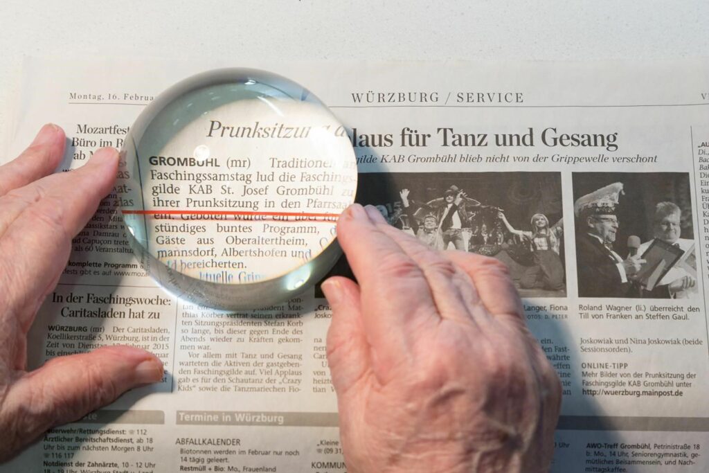 Seniorenhände beim Lesen mit Lupe