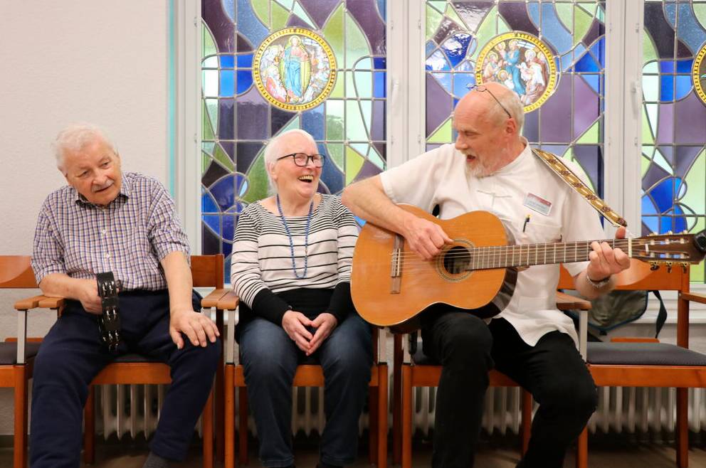 Betreuer mit Gitarre und Senior:innen