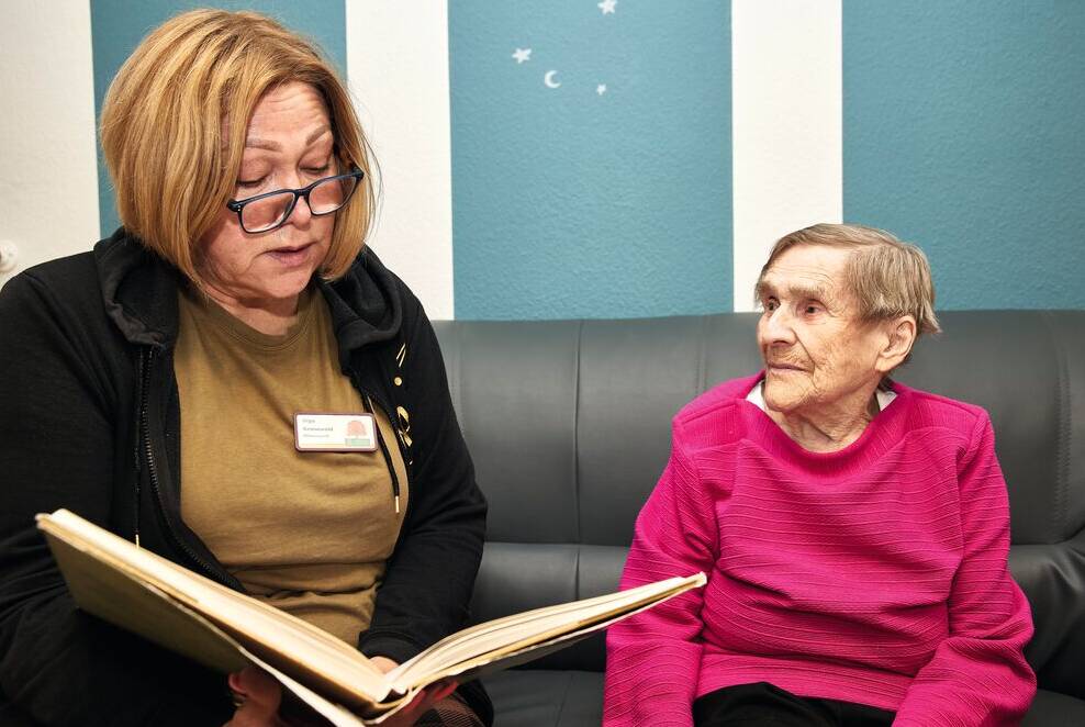 Betreuerin liest Seniorin vor