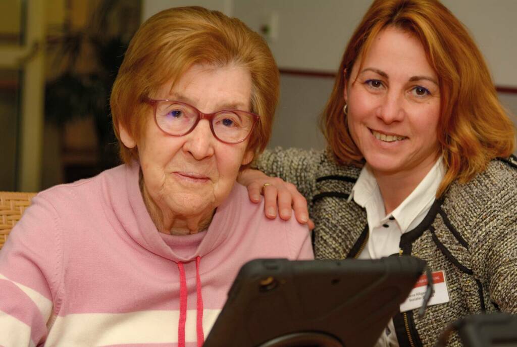 Seniorin mit jüngerer Frau vorm Tablet