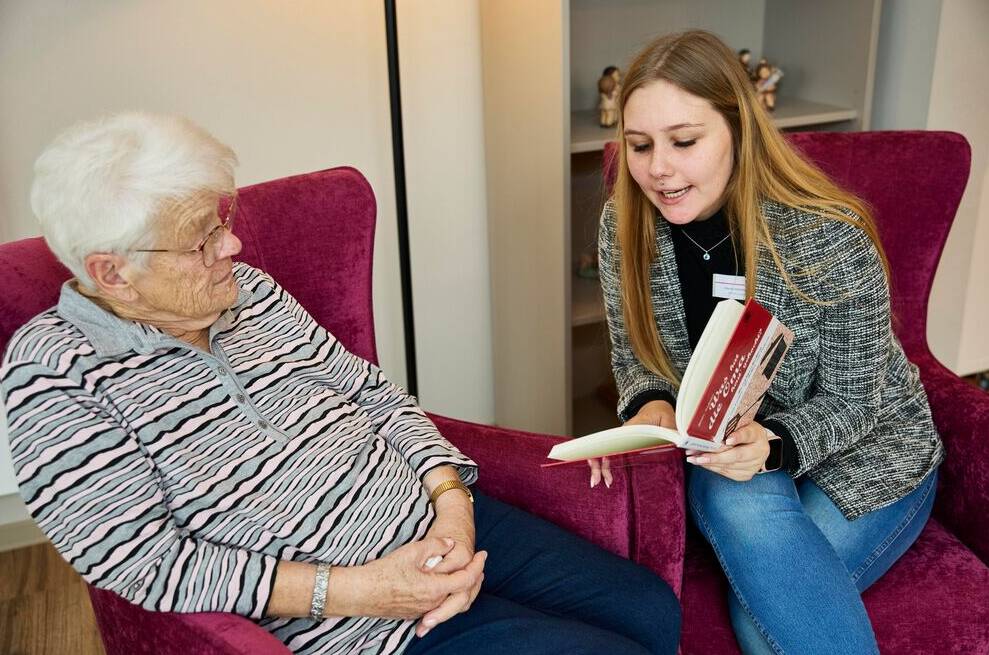 junge Frau liest Bewohnerin vor