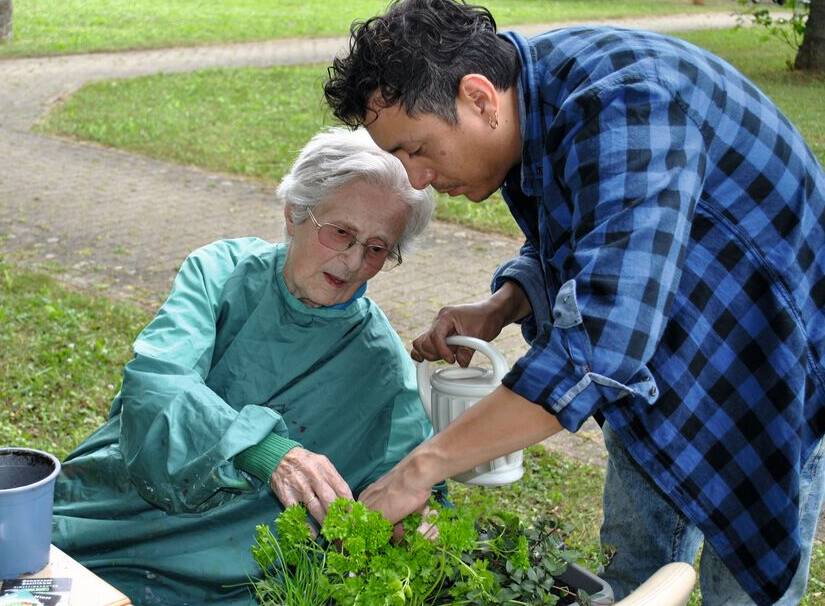 Seniorin und Mitarbeiter am Kräuterbeet