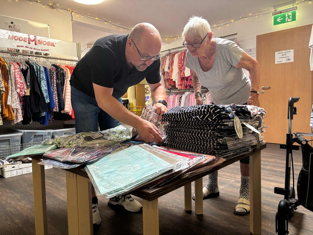 Seniorin bei der T-Shirt-Auswahl im Geschäft.