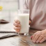 Seniorin mit einem Glas Buttermilich in der Hand