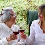 Mutter und Tochter stoßen im Garten mit Wein an