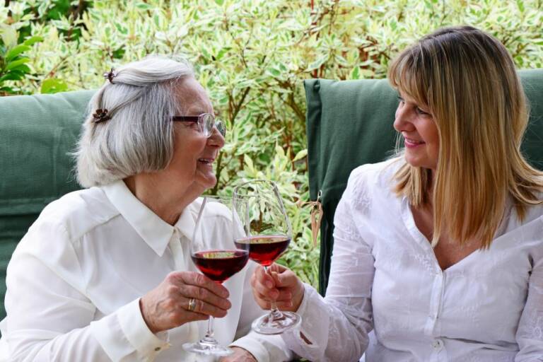 Mutter und Tochter stoßen im Garten mit Wein an