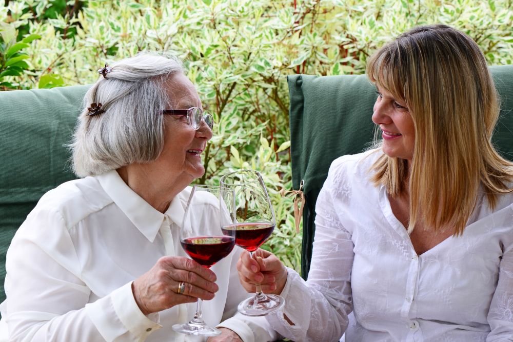 Mutter und Tochter stoßen im Garten mit Wein an