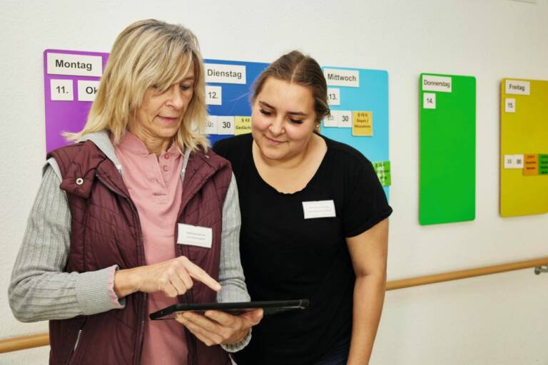 Kolleginnen schauen gemeinsam aufs Smartphone